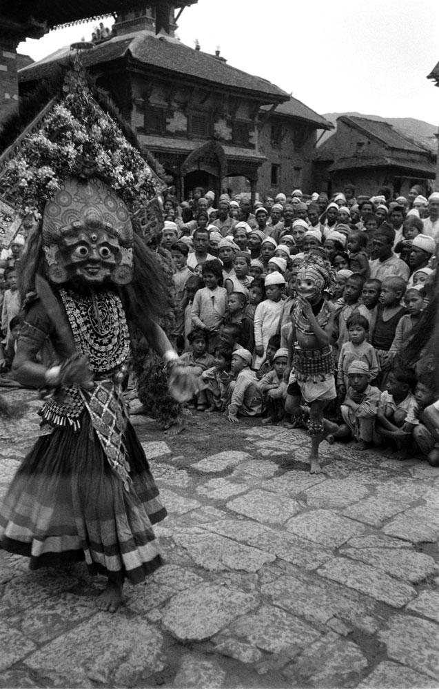Getting ready for heroes, devil dancers prance in Temple Square, Nepal, 1953.