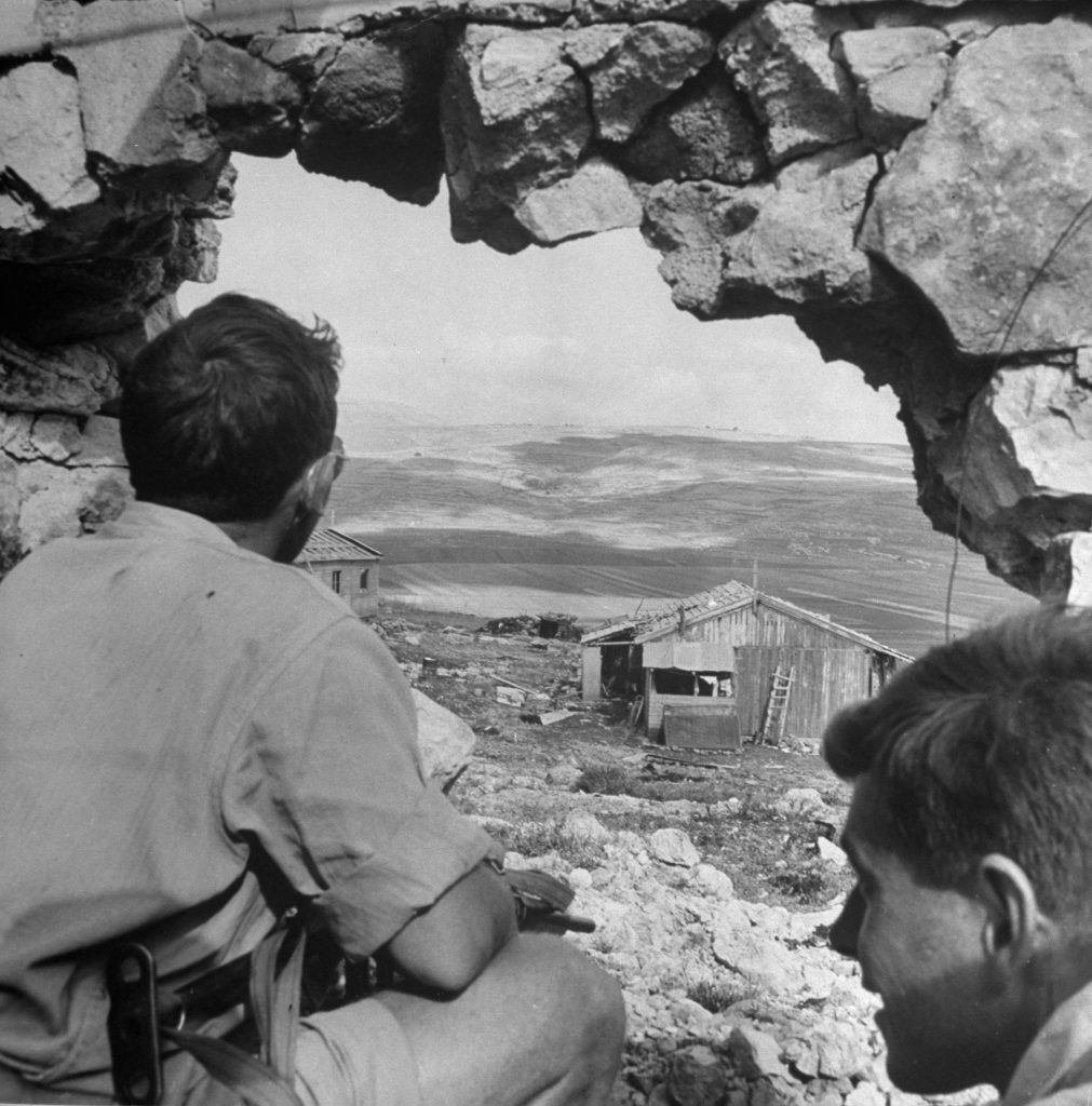Two men peer out of a hole in a bombed building, shortly after the establishment of the state of Israel, May 1948.