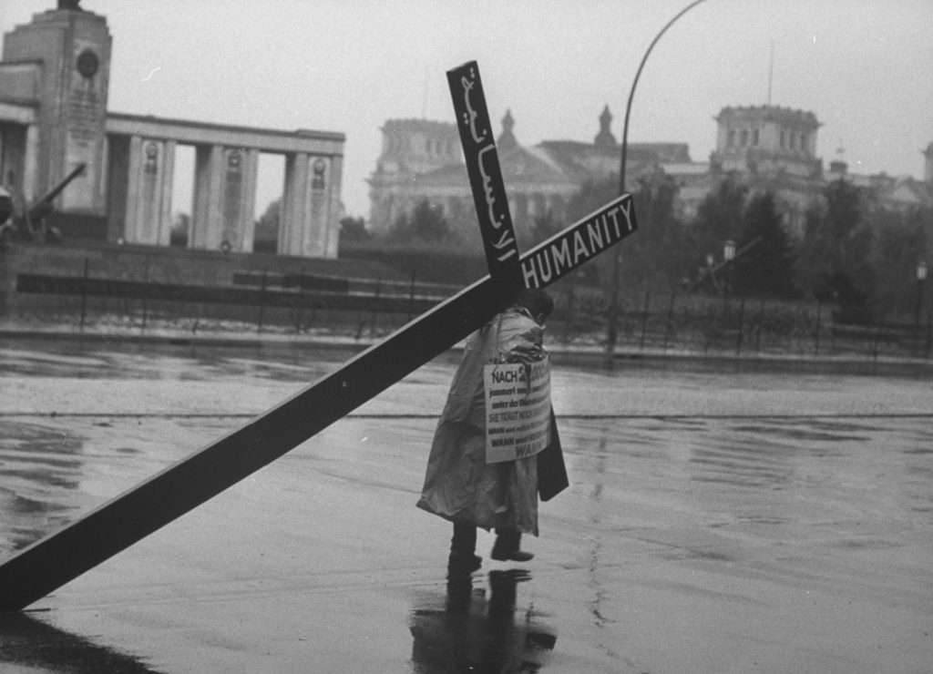 A Lebanese businessman carries cross in protest at the Berlin Wall