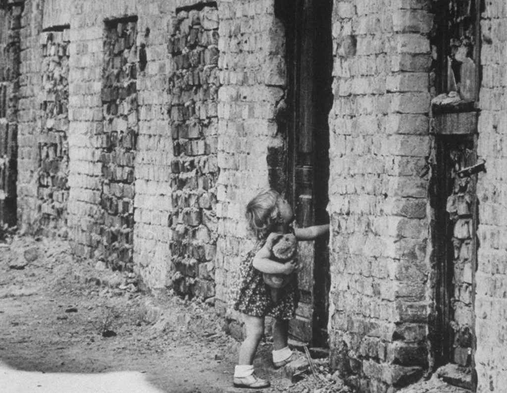 A West Berlin child struggles with a sealed door that has become a part of the Berlin Wall.